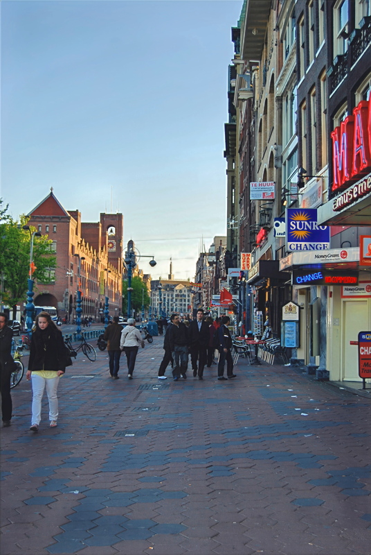 10 - A street scene in Amsterdam, likely the Zeedijk or a similar thoroughfare, featuring historic architecture, street-level shops, and tourists